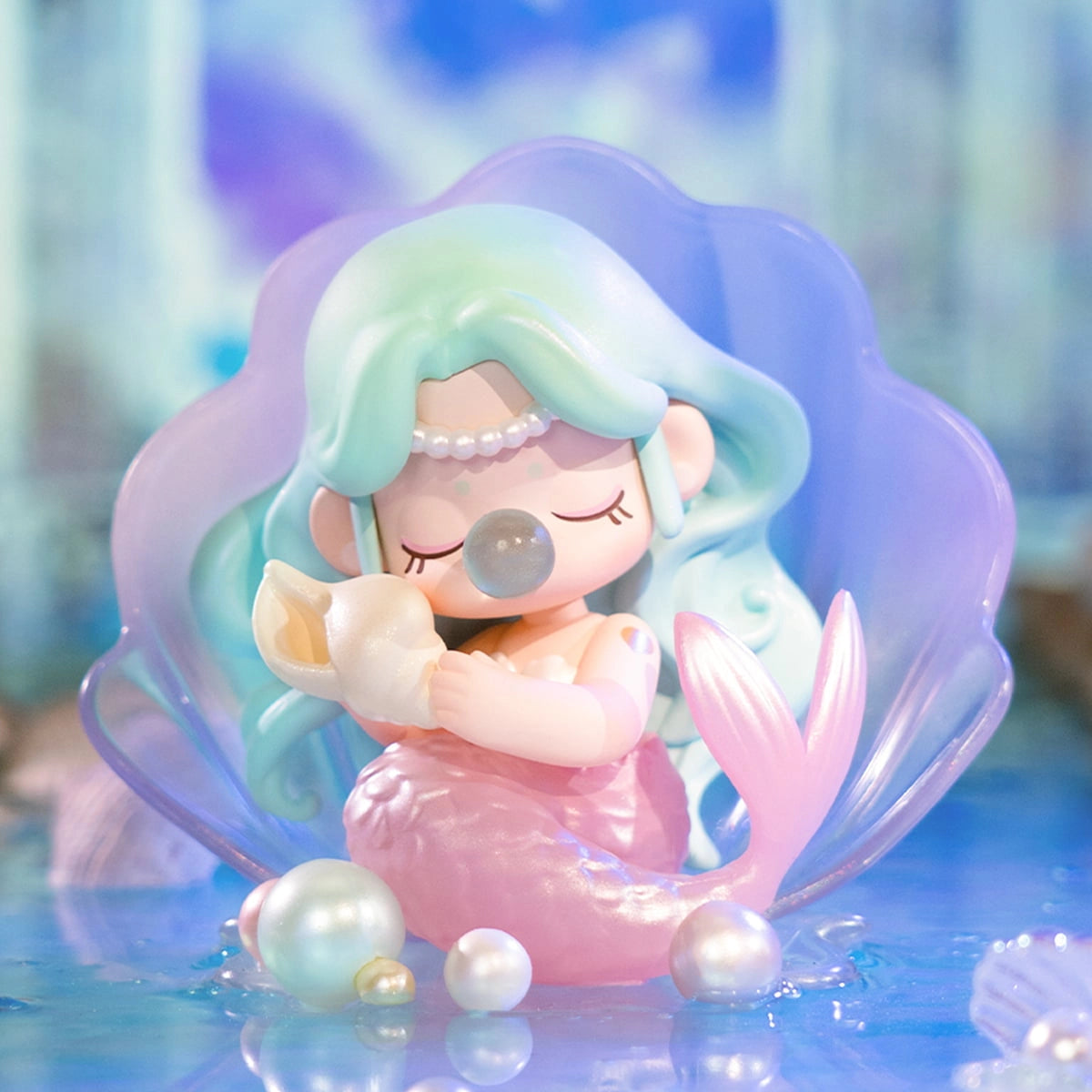 Nanci's Museum of Fantasy Blind Box Series: A mermaid figurine with mint hair, pink tail, and conch, seated in a purple shell among glossy pearls.