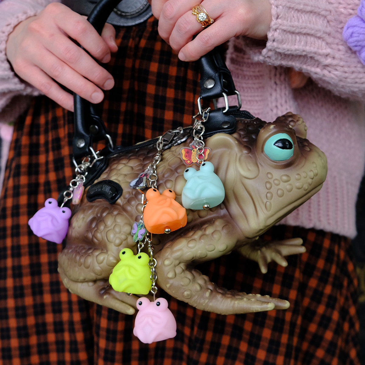 Fruggie the Toad Bag & Key Charms by Horrible Adorables, a toad-shaped handbag with pastel frog charms and black handles, held by a person in playful attire.