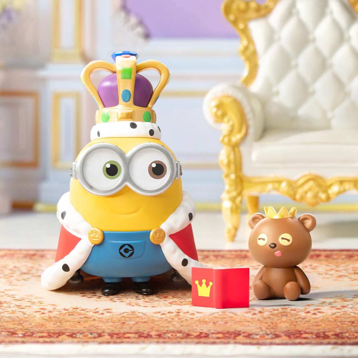 Minions Bedtime Stories by Bob and Tim Series Figure: King Minion with crown and cloak, accompanied by crowned teddy bear and book, set on ornate carpet.
