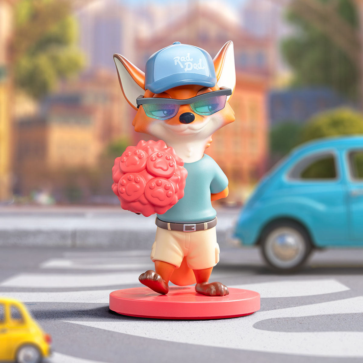 Disney Zootopia: Next Adventure Series Figures - Preorder. Stylized fox figurine in casual attire holding a red object, set in a playful miniature street scene.