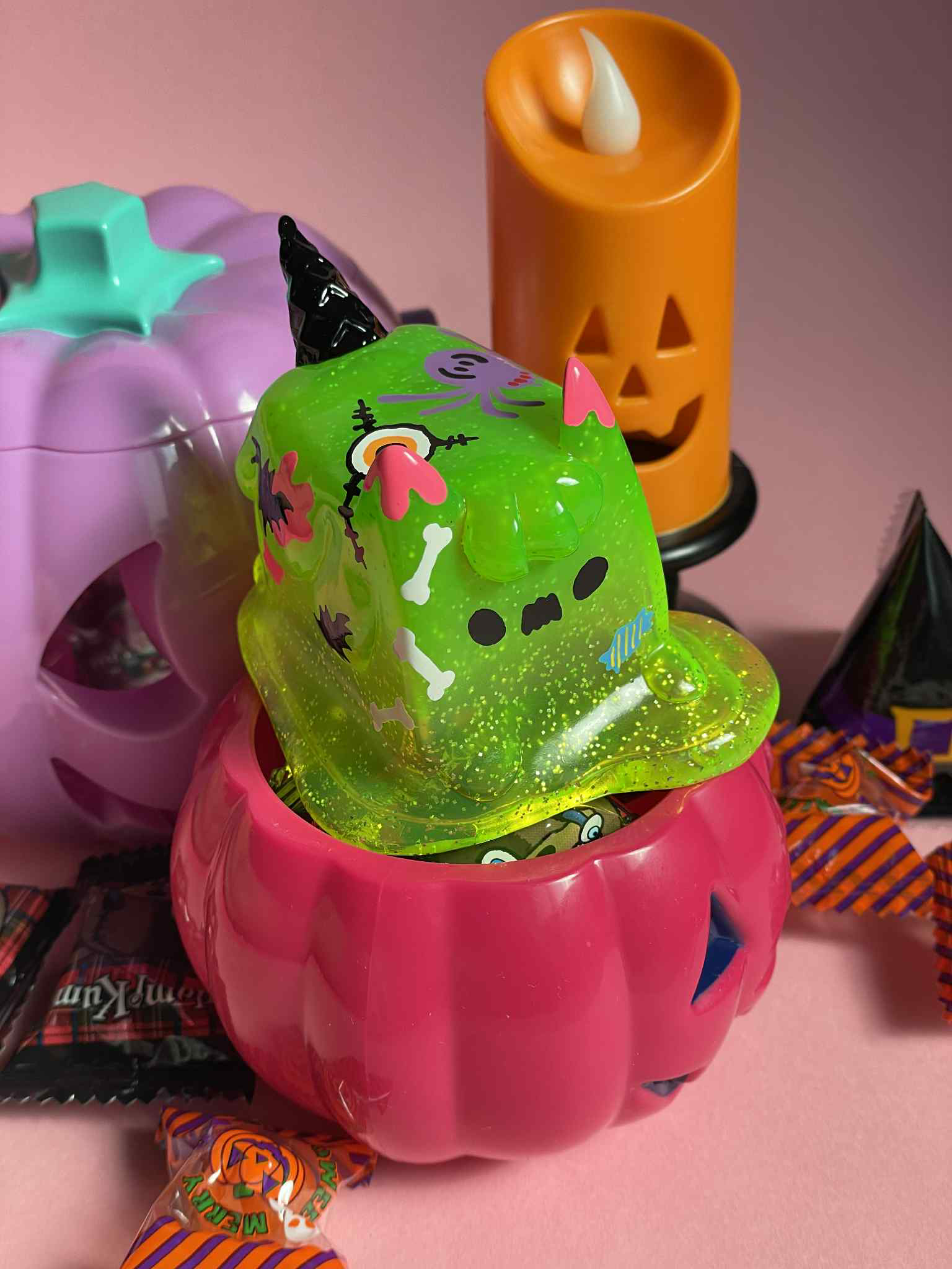 Halloween Ice Cream Cat by Rato Kim - Preorder: A pink pumpkin bucket filled with candy, topped with a monster-slime toy, amidst Halloween-themed decor.
