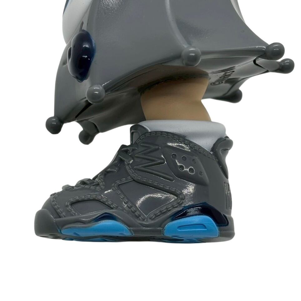 Close-up of Kick Specter - grey by MARK's, showcasing a stylized vinyl figurine's foot adorned in a detailed grey-and-blue, Jordan 6-style sneaker.