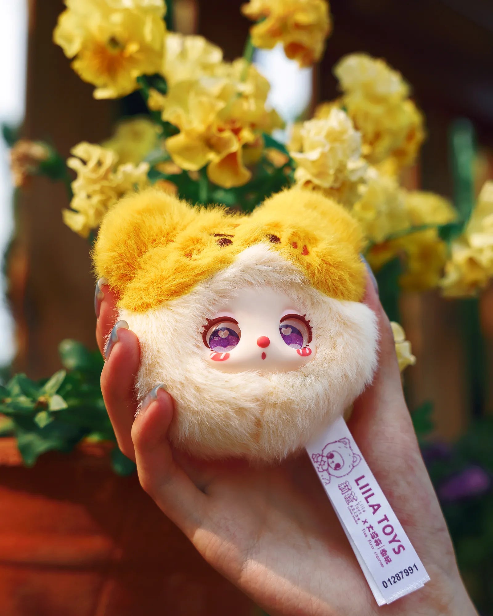 Liila’s Garden Tea Party Mini Plush features a yellow-eared, cream-bottomed toy with sparkly eyes, held before yellow flowers, tagged LILA TOYS.