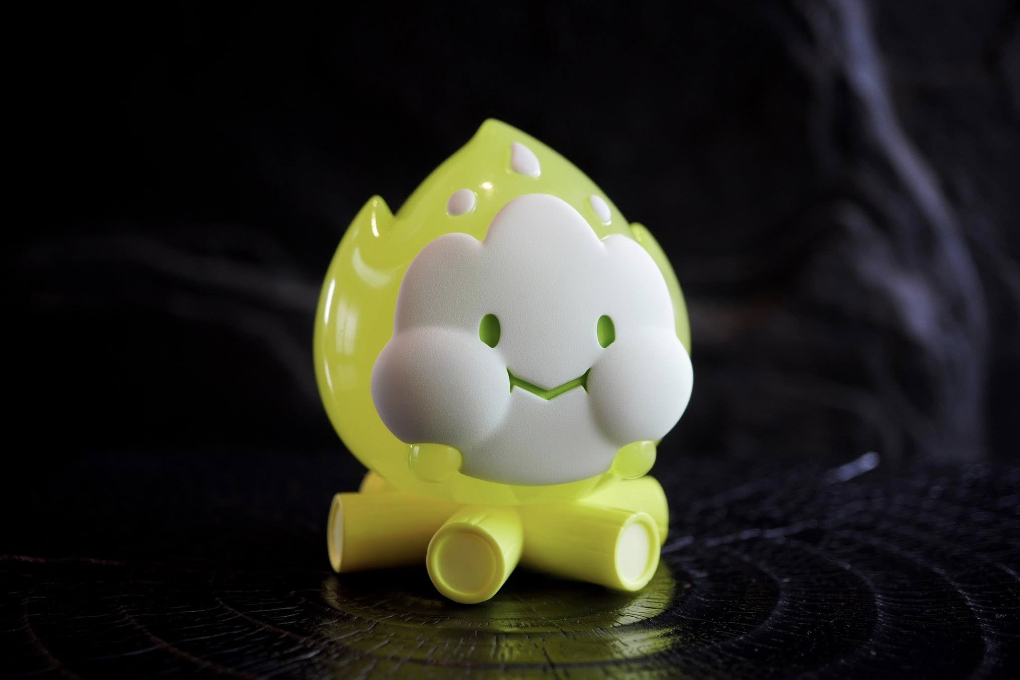 FLAMEY BON - Green Glow by MUPA Toy features a neon flame-cloud figurine on log stumps, with a matte face, eyes, and smile. Preorder available.