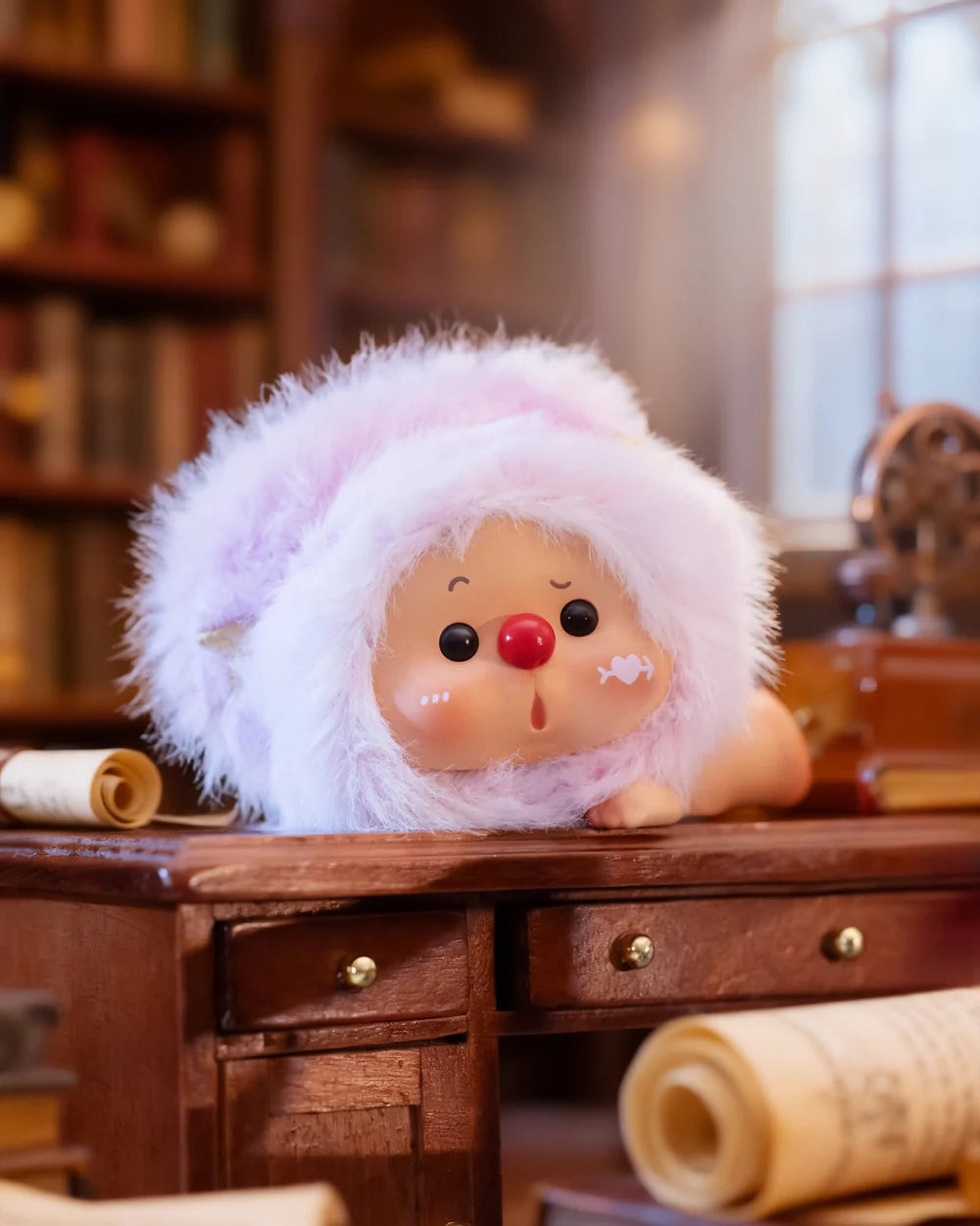 OYO Constellation Story Hipper Series Mini Blind Box figurine, round-faced with big eyes in pink hood, on desk with scrolls in cozy library setting.
