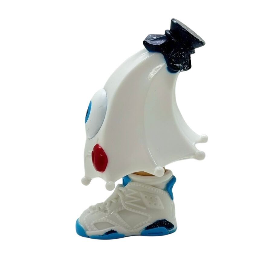 Kick Specter - white by MARK's: A 12.5cm cartoon-style banana figure with a crown hat, one eye, red cheek, standing on a sneaker resembling an Air Jordan 6.