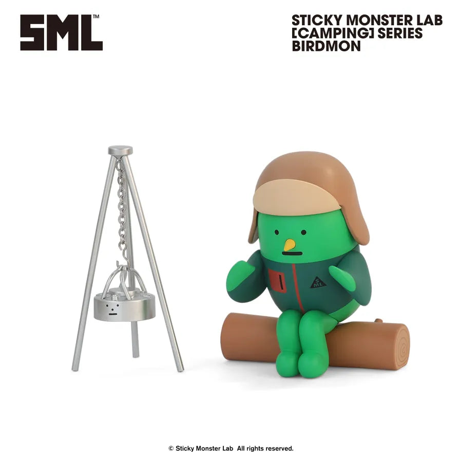 Sticky Monster Lab [Camping] Series Birdmon figure, a green, round vinyl toy in a jacket and hat, seated on a log with campfire cooking setup.