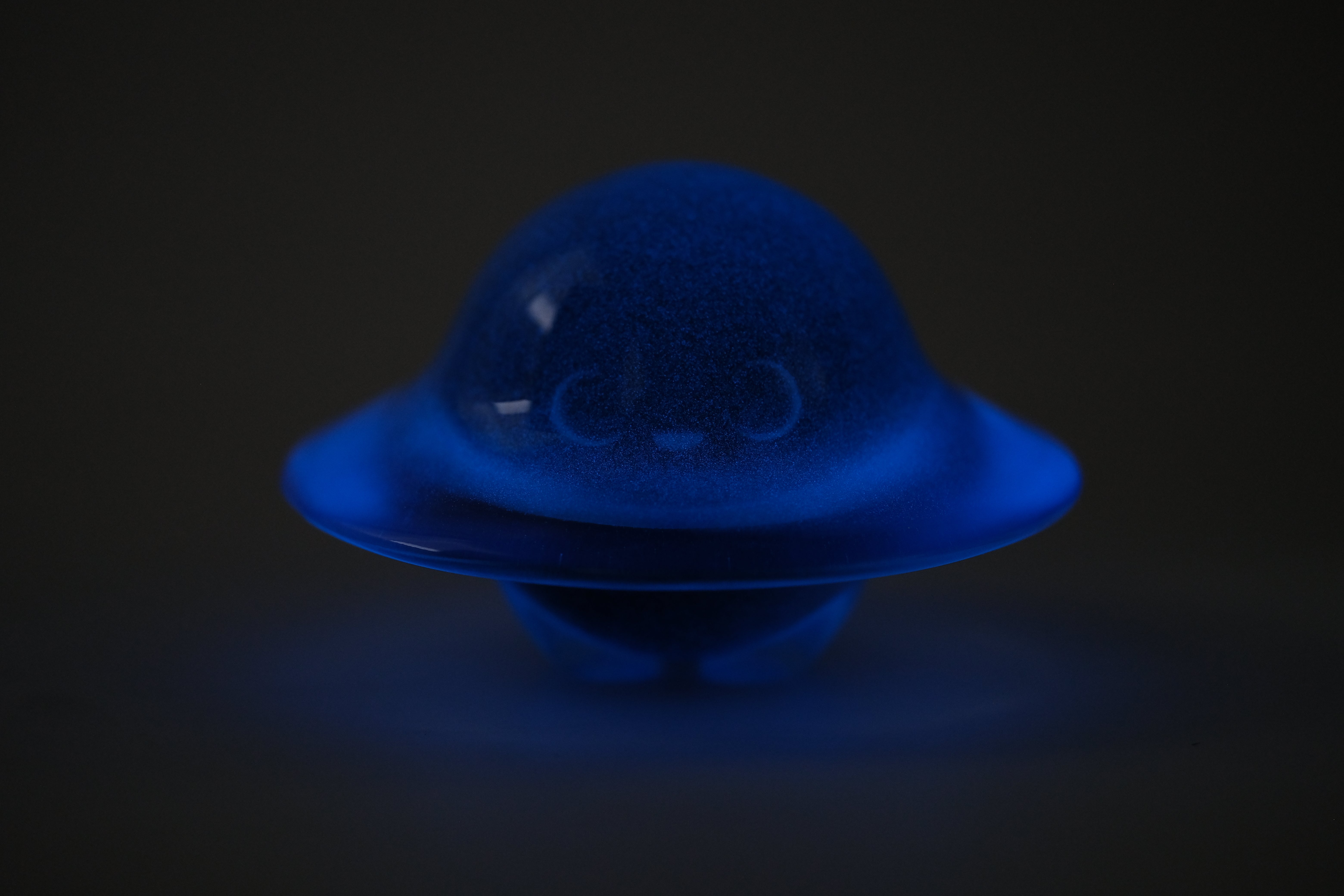 Glow in the Darkmite! by Yutoos: A 3.5 resin art-toy shaped like a smiling, dome-shaped creature, glowing vibrantly against a dark background.