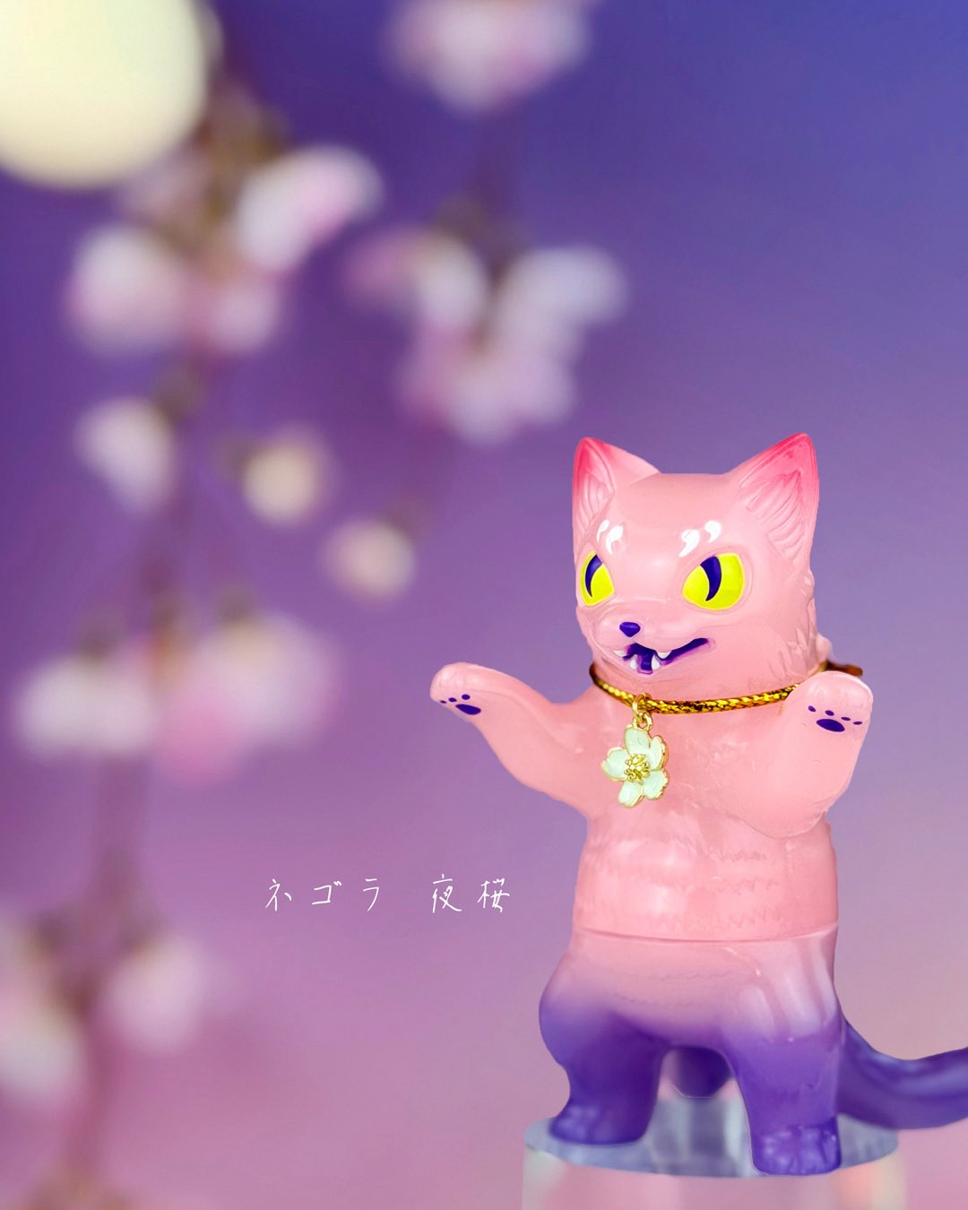Negora Night Sakura GID by Konatsu, a 3.8-inch sofubi cat figure with bright yellow eyes and a cherry-blossom pendant, available for preorder.