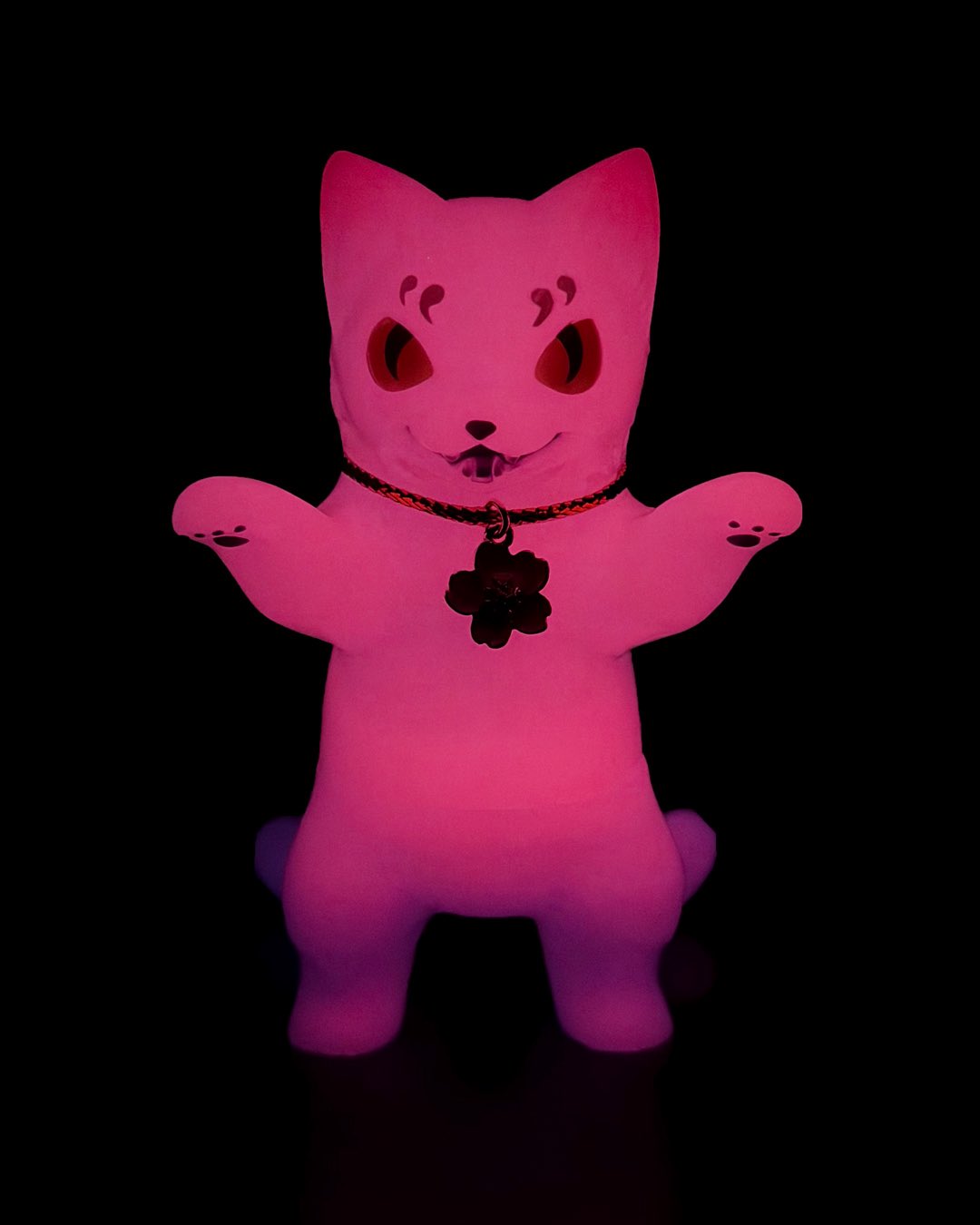 Negora Night Sakura GID by Konatsu, a glowing 3.8-inch sofubi cat figurine, mischievously grins with raised paws and flower charm collar. Preorder for May 2026 shipment.