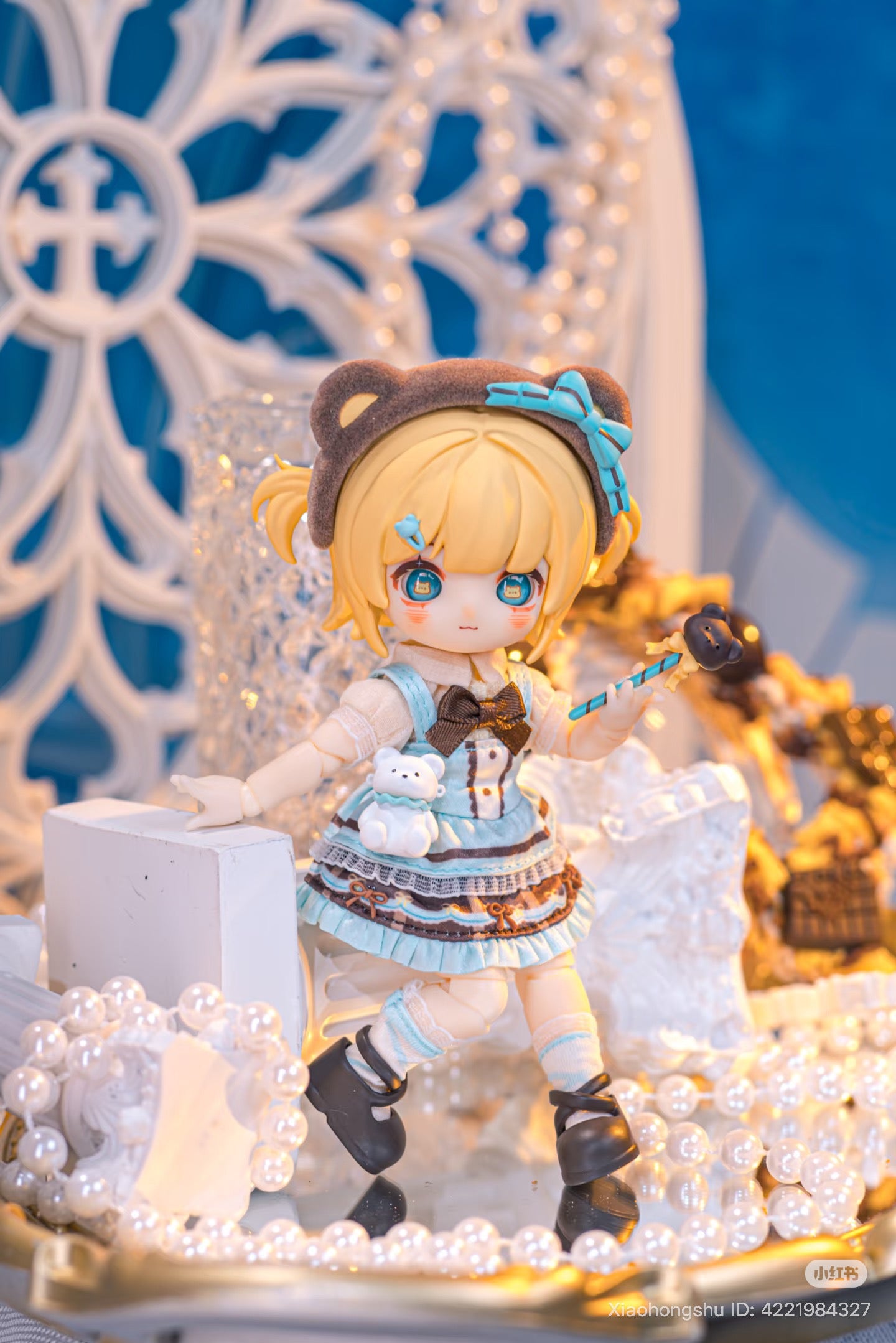 NAGI: The Phantom Record Series Figure featuring chibi doll with blonde pigtails in a pastel-blue dress, bear-ear headband, and candy-apple wand amid faux pearls.