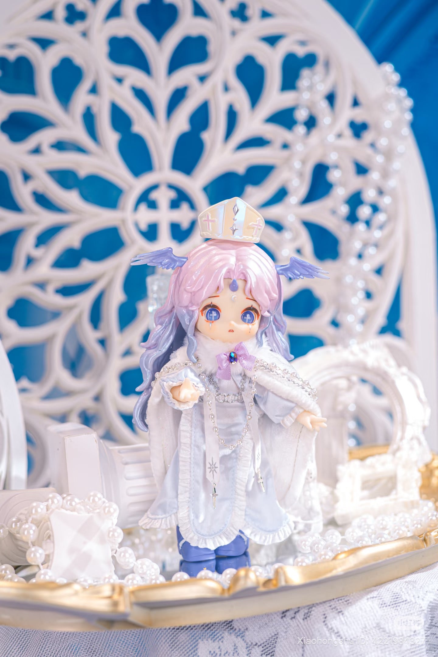 NAGI: The Phantom Record Series Articulated Figure in angelic-bishop attire with pastel hair, delicate accessories, and ornate robe on decorative tray, available for preorder.