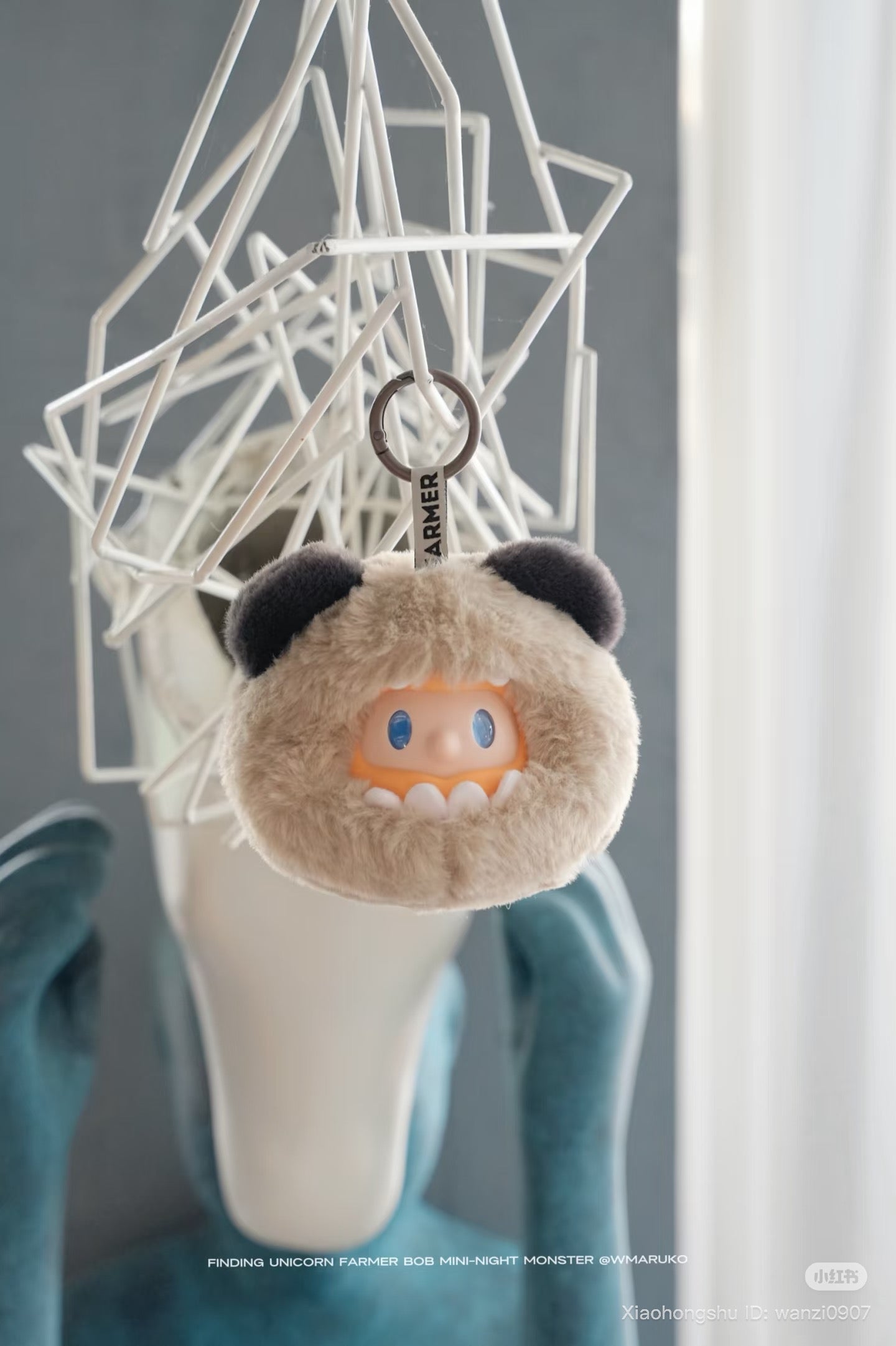 Farmer BOB MINI- NIGHT Monster Blind Box Plush Keychain, a fuzzy beige creature with a cartoon face, hangs from a geometric frame. Preorder for November 2025.