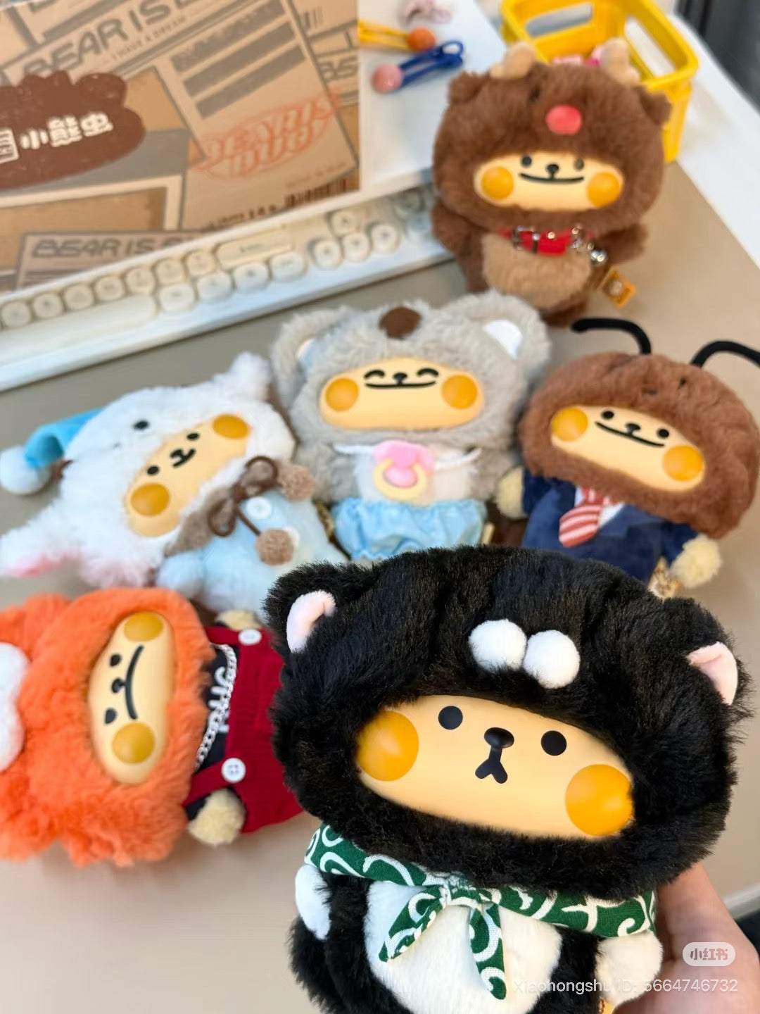 Bearisbug plush key-chain toys in animal costumes on a desk, part of a blind box series with 6 designs and 1 secret option.