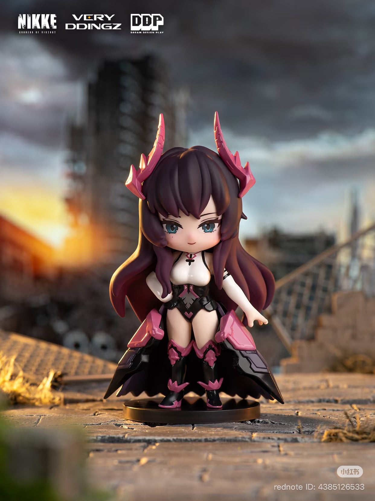 Chibi figure from NIKKE: Goddess of Victory Blind Box, showcasing a stylized female with purple-brown hair and an armored outfit, atop a stone base.