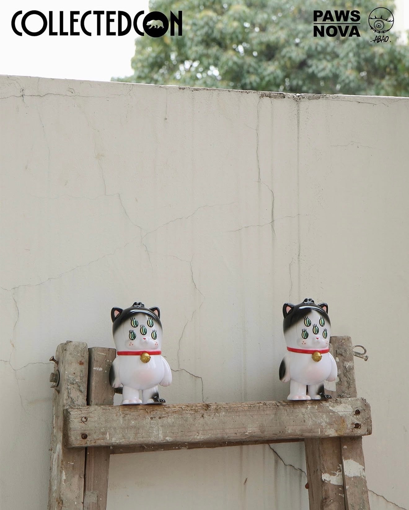 CollectedCon Abao Beans Exclusive figurines, preorder vinyl figures with distinctive black markings, red collars, and large green eyes, displayed on a wooden stepladder. Ships May 2026.