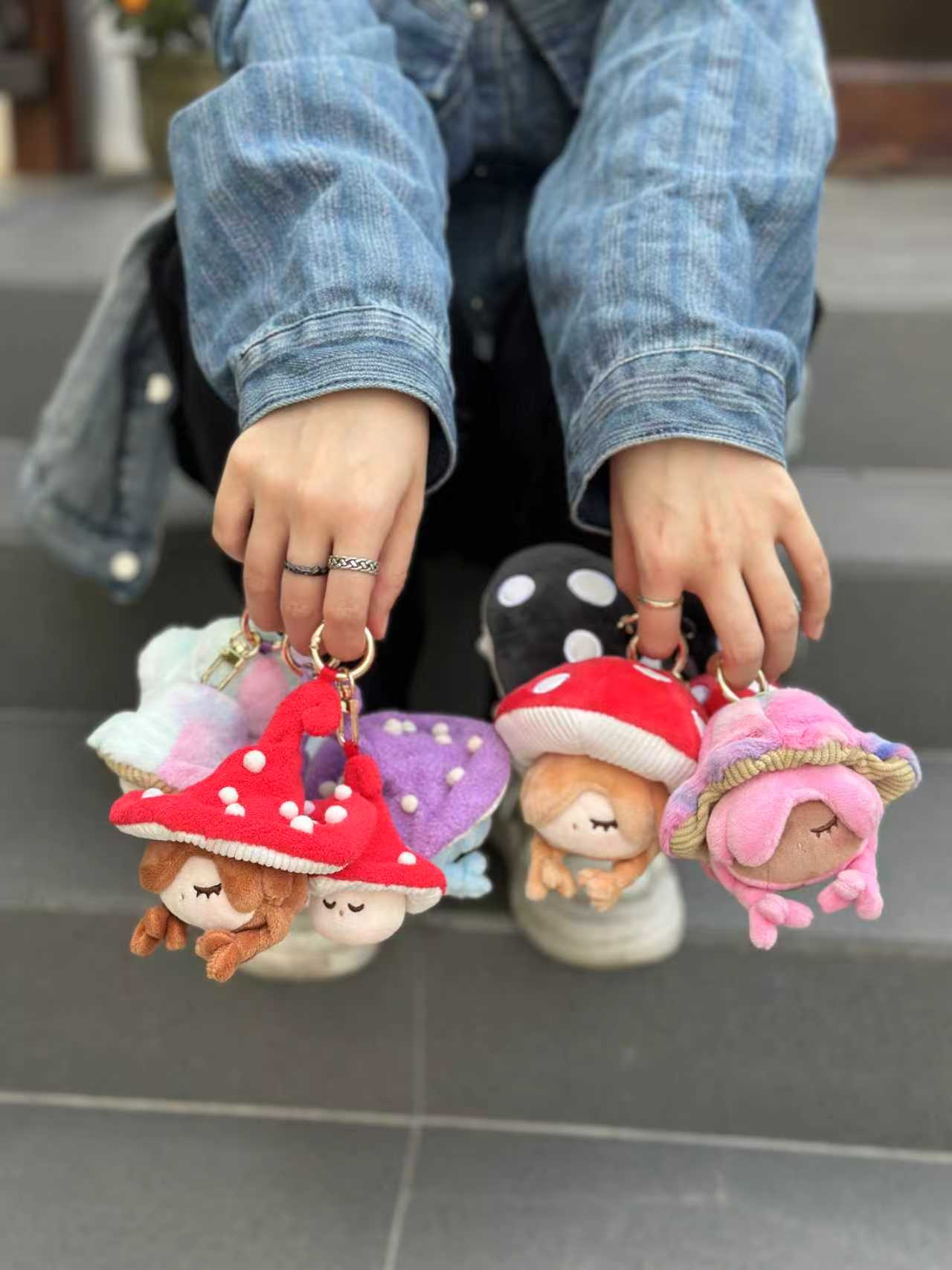 Person holding Little Mushroom Plush Pendant Blind Box key-chains, featuring sleepy dolls under mushroom caps, showcasing available designs.