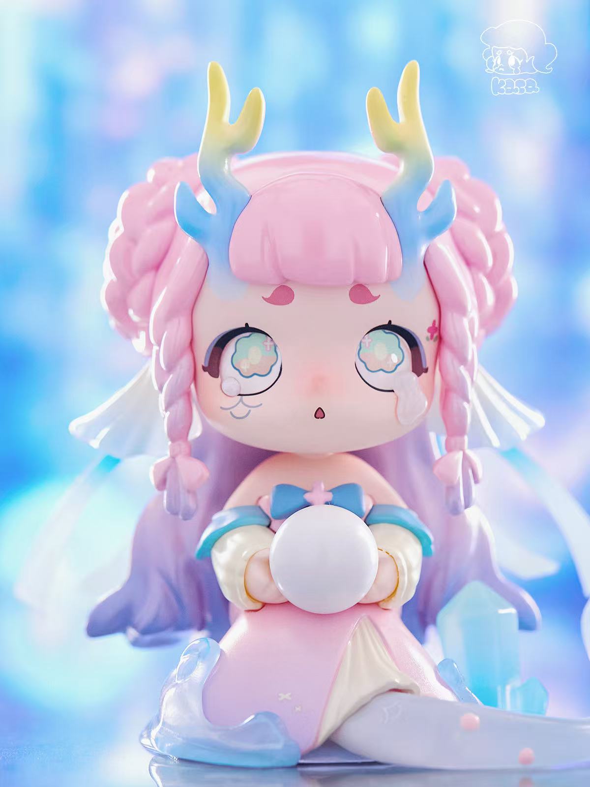 KASA 2.0 - Mystic Tales Blind Box Series figure with pastel colors, anime eyes, antler-like horns, and translucent accents clutching a white orb.