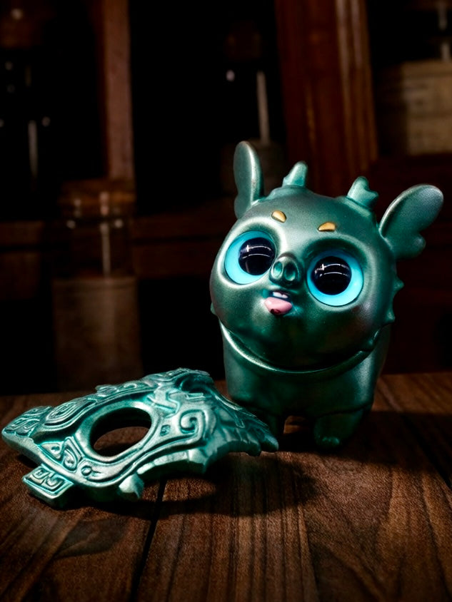 Little Bronze Taotie by HOTRU - Preorder: A teal vinyl toy with glossy blue eyes, horns, a tongue out, and a matching detachable decorative mask.
