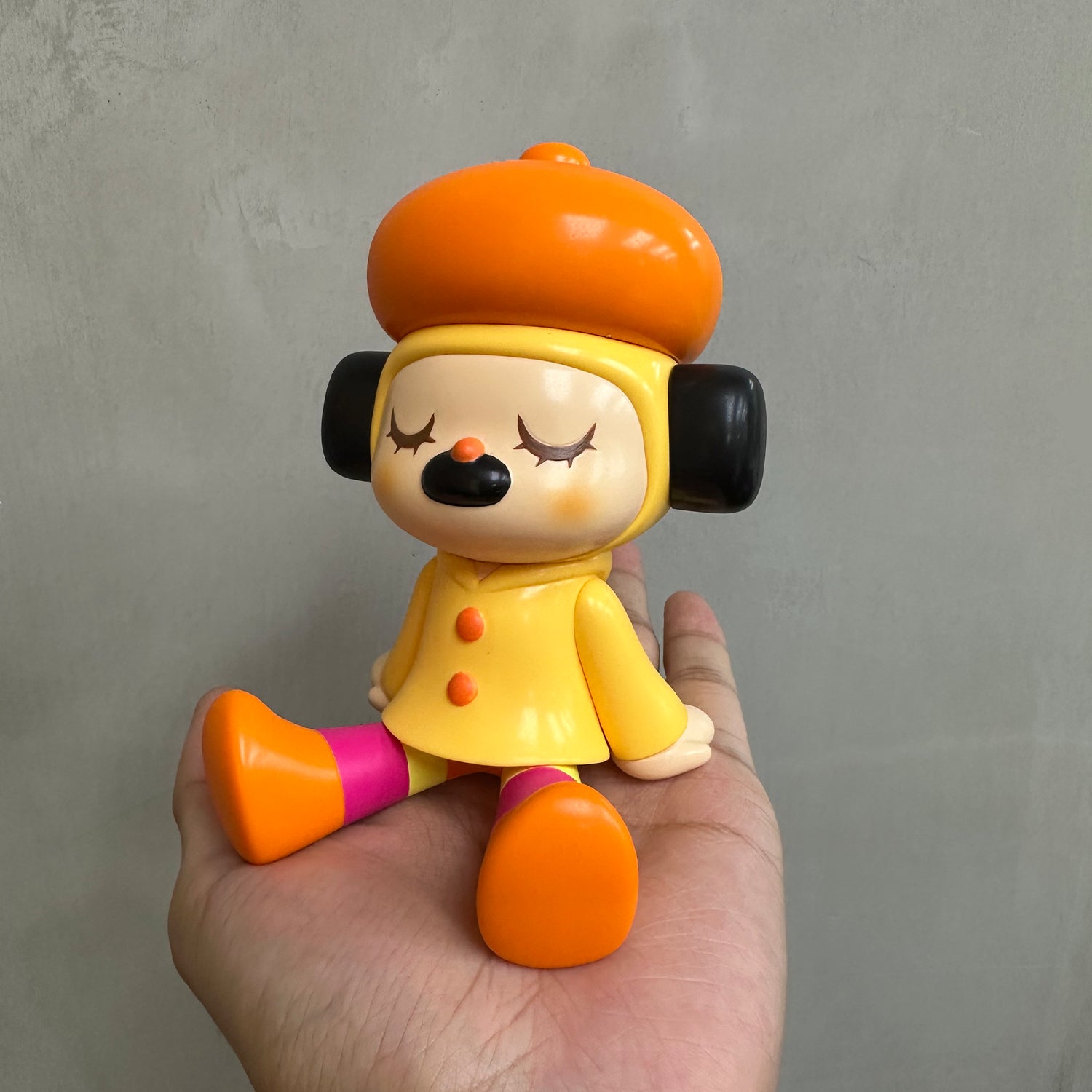 GREENIE OHIGEnoPON EDITION - Preorder: Soft vinyl toy with closed eyes, wearing an orange beret, yellow coat, and striped leggings in hand. Designed by Too Natthapong.