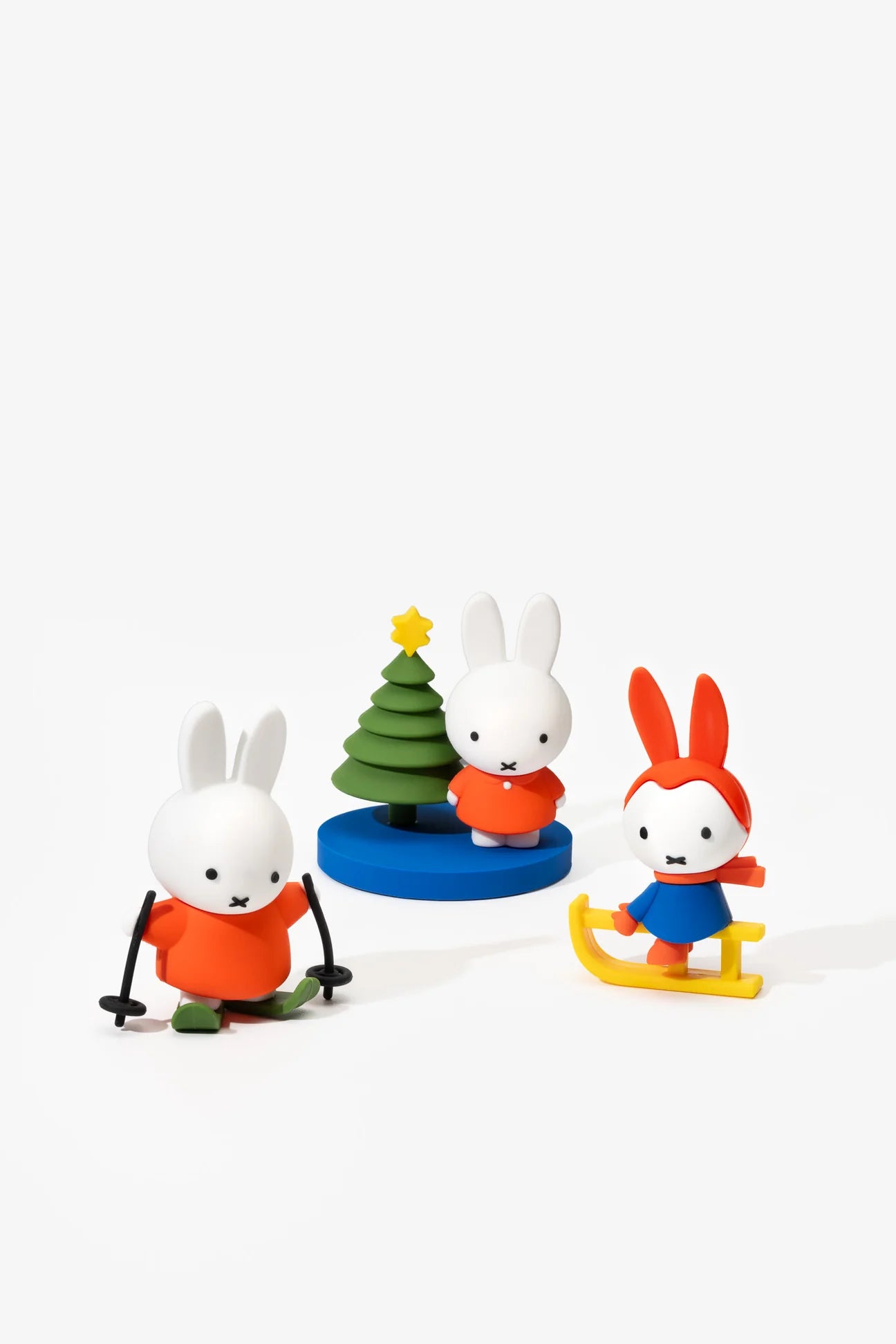 Three Miffy figurines in bright winter outfits: skiing, with a Christmas tree, and on a sled, from the Miffy in the Snow Blind Box Figure collection.