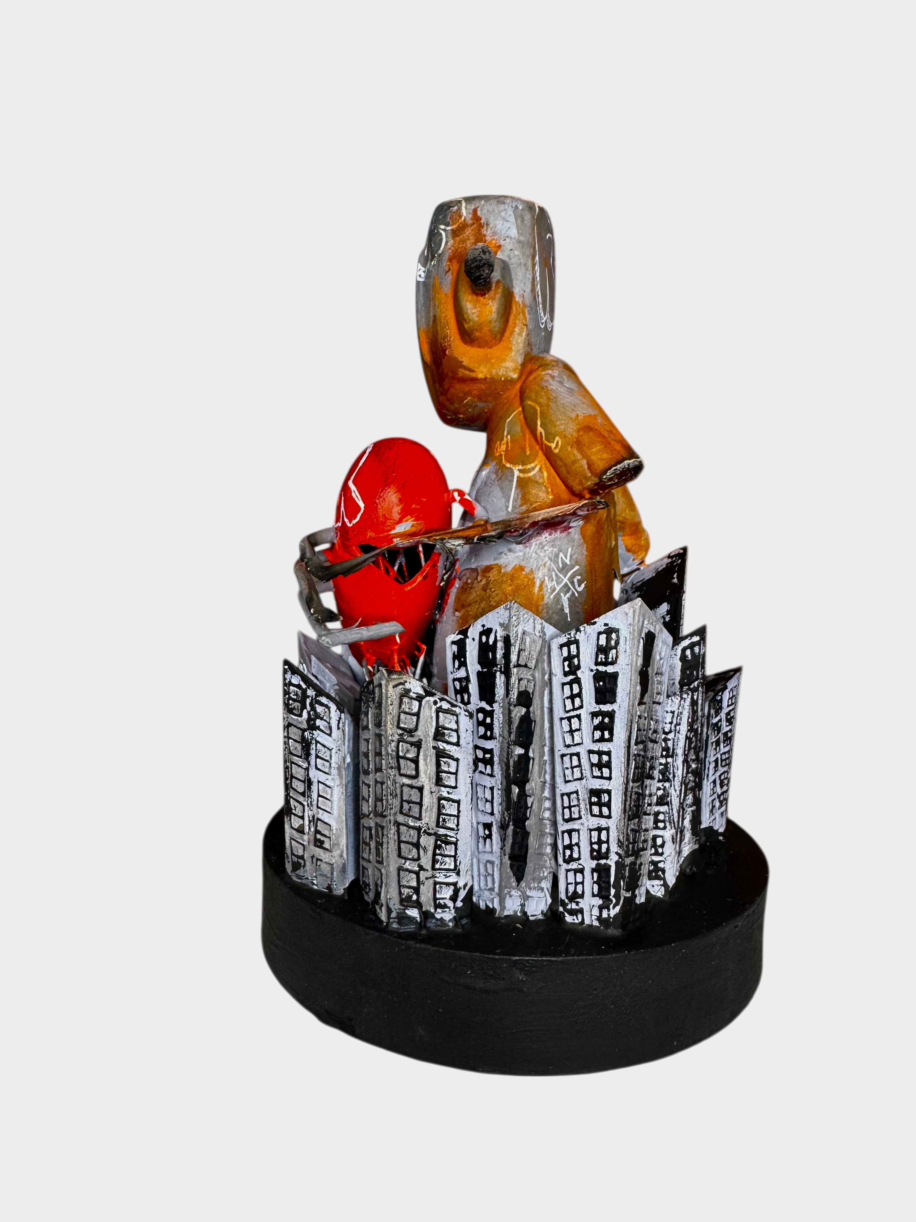 Time Will Tell - Still standing by Chris RWK: a gold humanoid sculpture on a city-themed base, clutching a vivid red heart bound with metal wires.