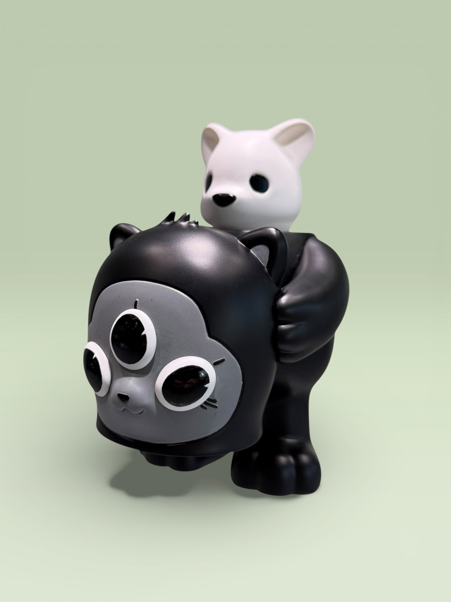 CollectedCon Luke Chueh Beans Exclusive: A black vinyl toy with cat-like ears, three eyes, and a small white figure on its back. Preorder for May 2026.