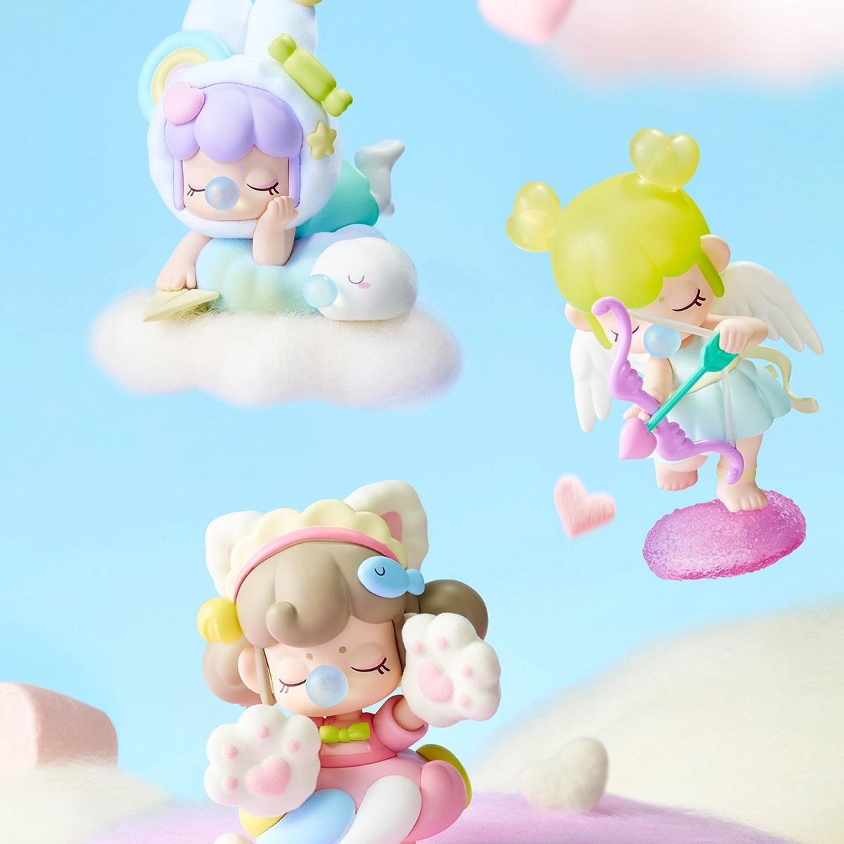 Nanci's Sweet Time Blind Box Series features dreamy figurines: unicorn child, cupid, and cat-costumed child, each on pastel clouds reflecting a kawaii vinyl-toy aesthetic.