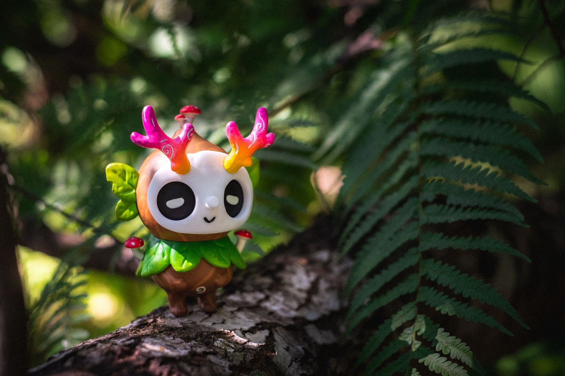 Ori Muffinn: The Wooden Brown toy perched on a mossy log, features a resin body with rainbow antlers and mushrooms, available for preorder.