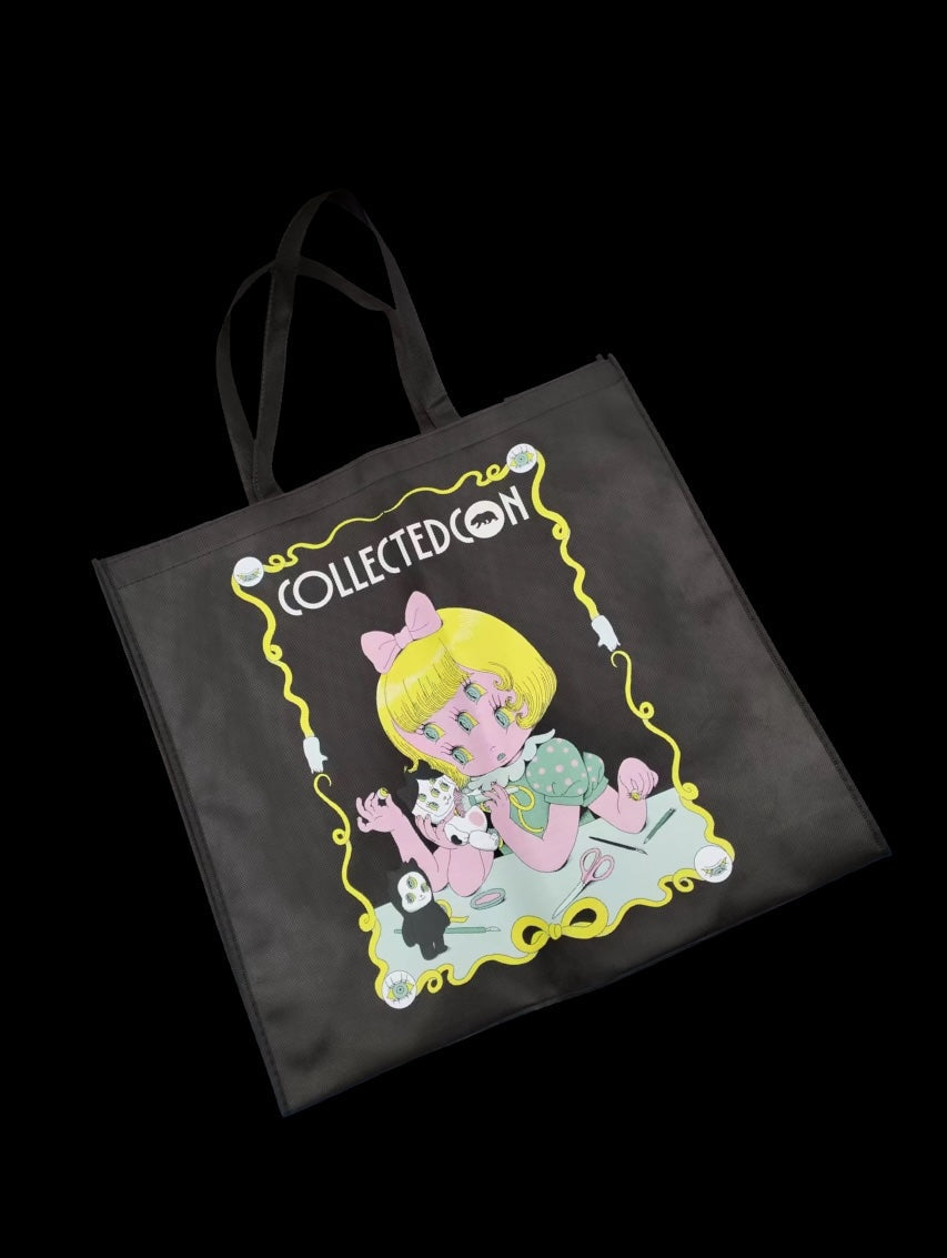 CollectedCon LA Bag - Preorder features a surreal illustration of a girl crafting at a table, capturing the whimsical essence of Strangecat Toys.