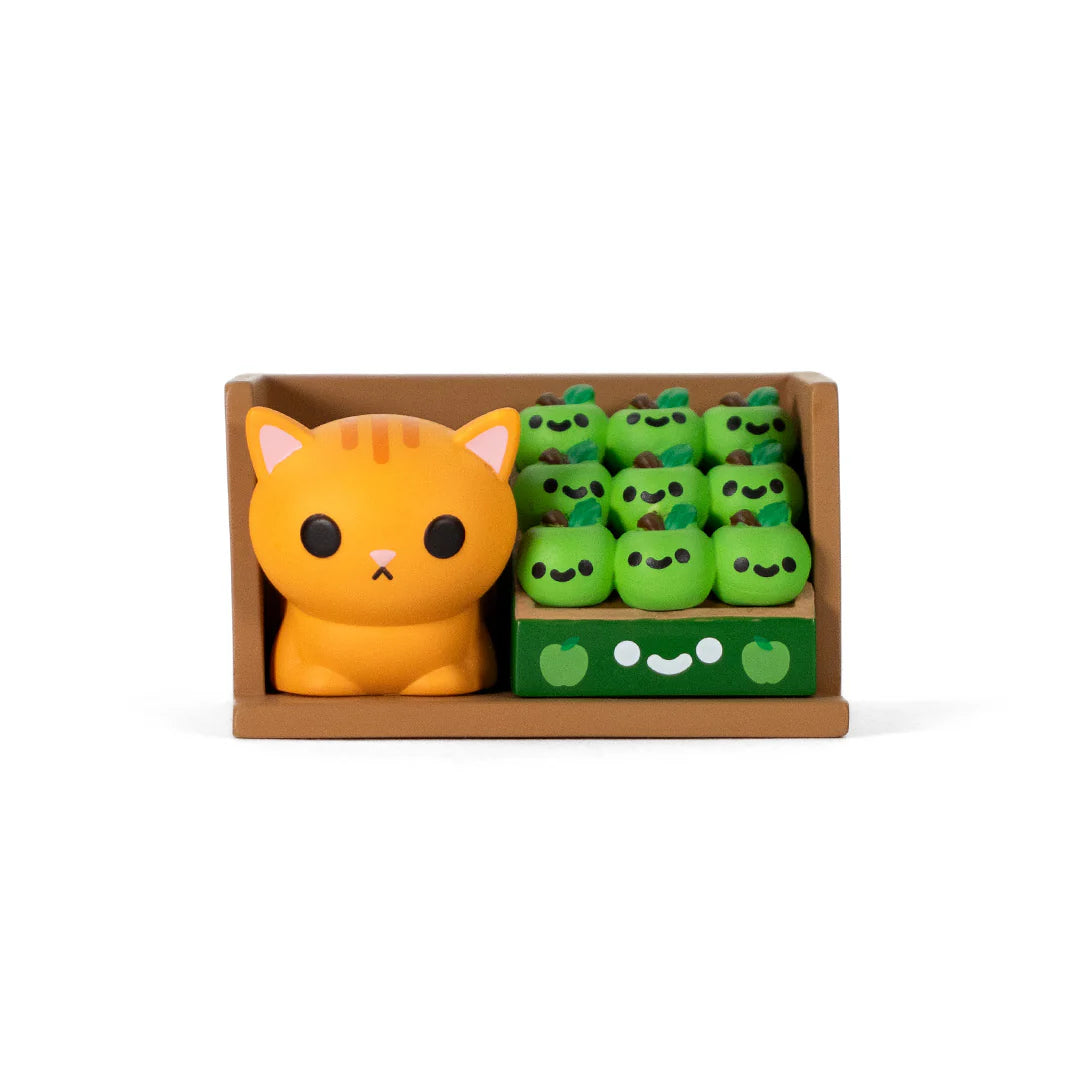Bodega Kitties Mystery Series 2 Boxes by 100% Soft features a chubby cat figure and a crate of smiling apple figures in a two-compartment display.
