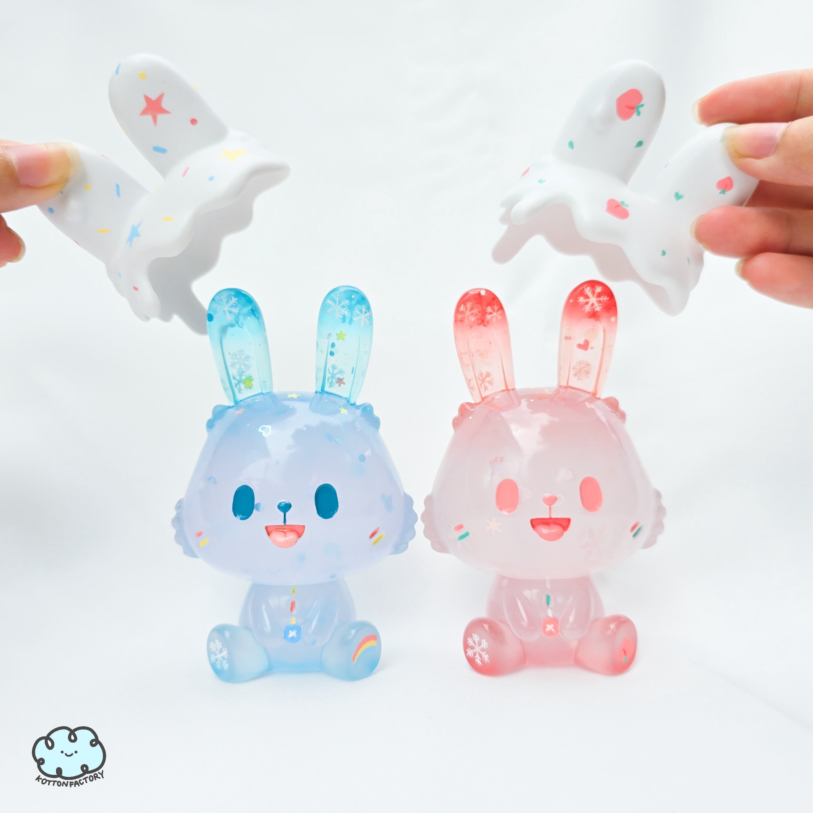 Hand holding a limited edition Snow Robin toy by Kotton Factory, featuring a pink resin figure that glows in the dark, from Strangecat Toys.