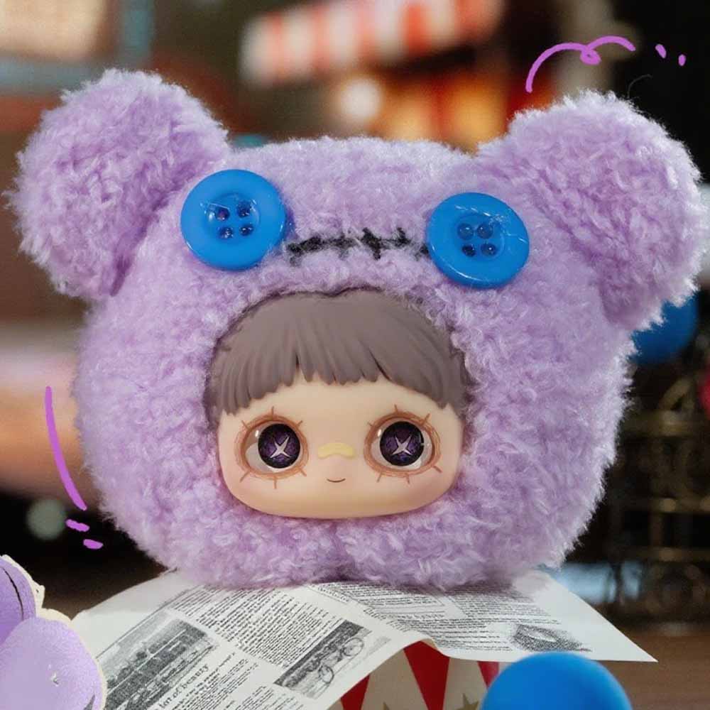 MayMei Crazy Circus Series Plush Keychain Blind Box featuring a fuzzy purple bear head with a vinyl doll face and button eyes on a newspaper-wrapped box.