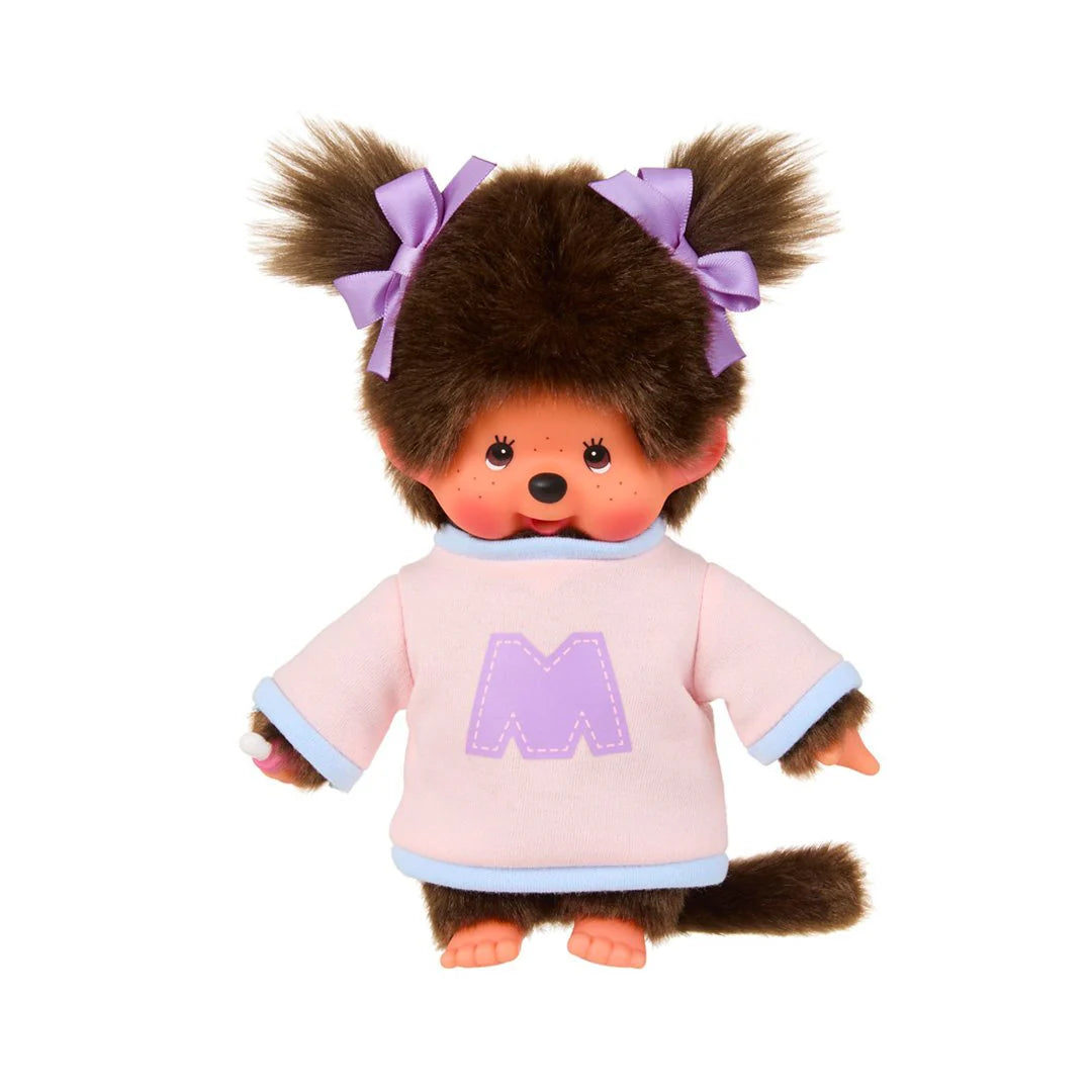 Monchhichi Girl - Bi-Colored Sweater Plush Toy featuring a furry brown body, plastic face, and hands, wearing a stylish sweater with pigtails tied by purple ribbons.