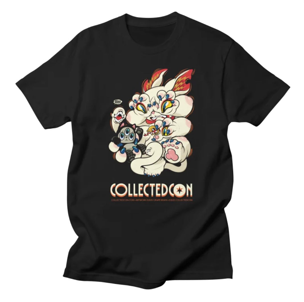 CollectedCon 2025 Shirt featuring a cartoonish, many-eyed cat-like monster clutching a plush figure, printed on a Gildan Soft Style T-shirt.