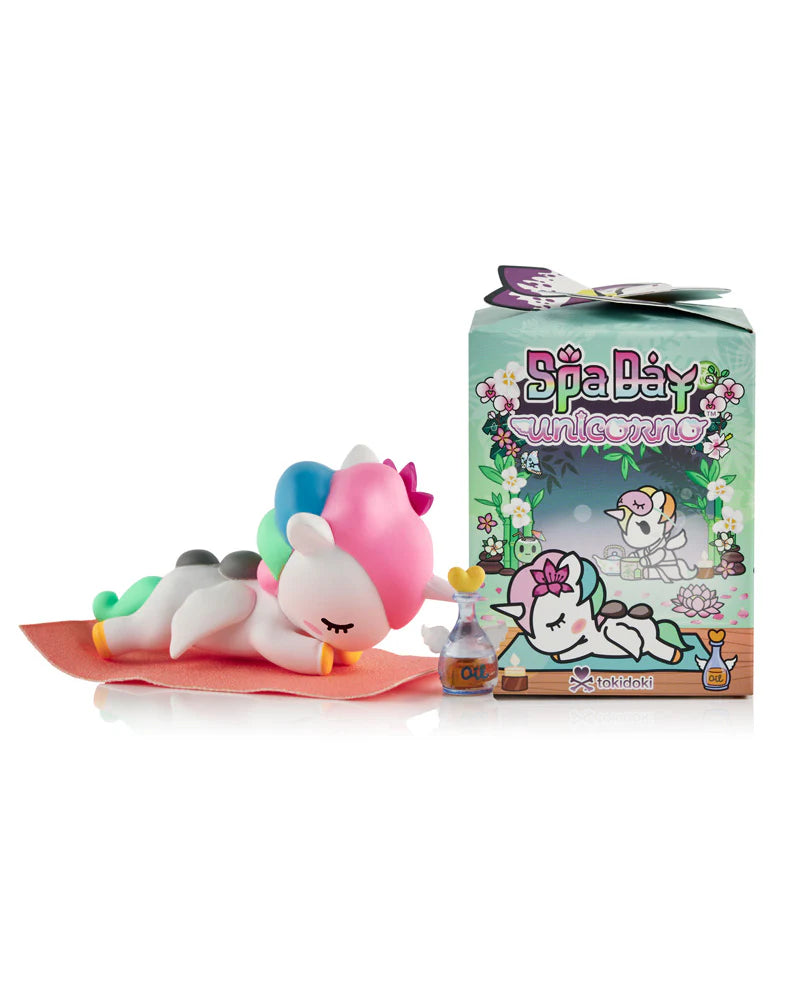 Spa Day Unicorno collectible figure on an orange towel with hot stones and oil bottle, next to its floral-themed box. Preorder now at Strangecat Toys.