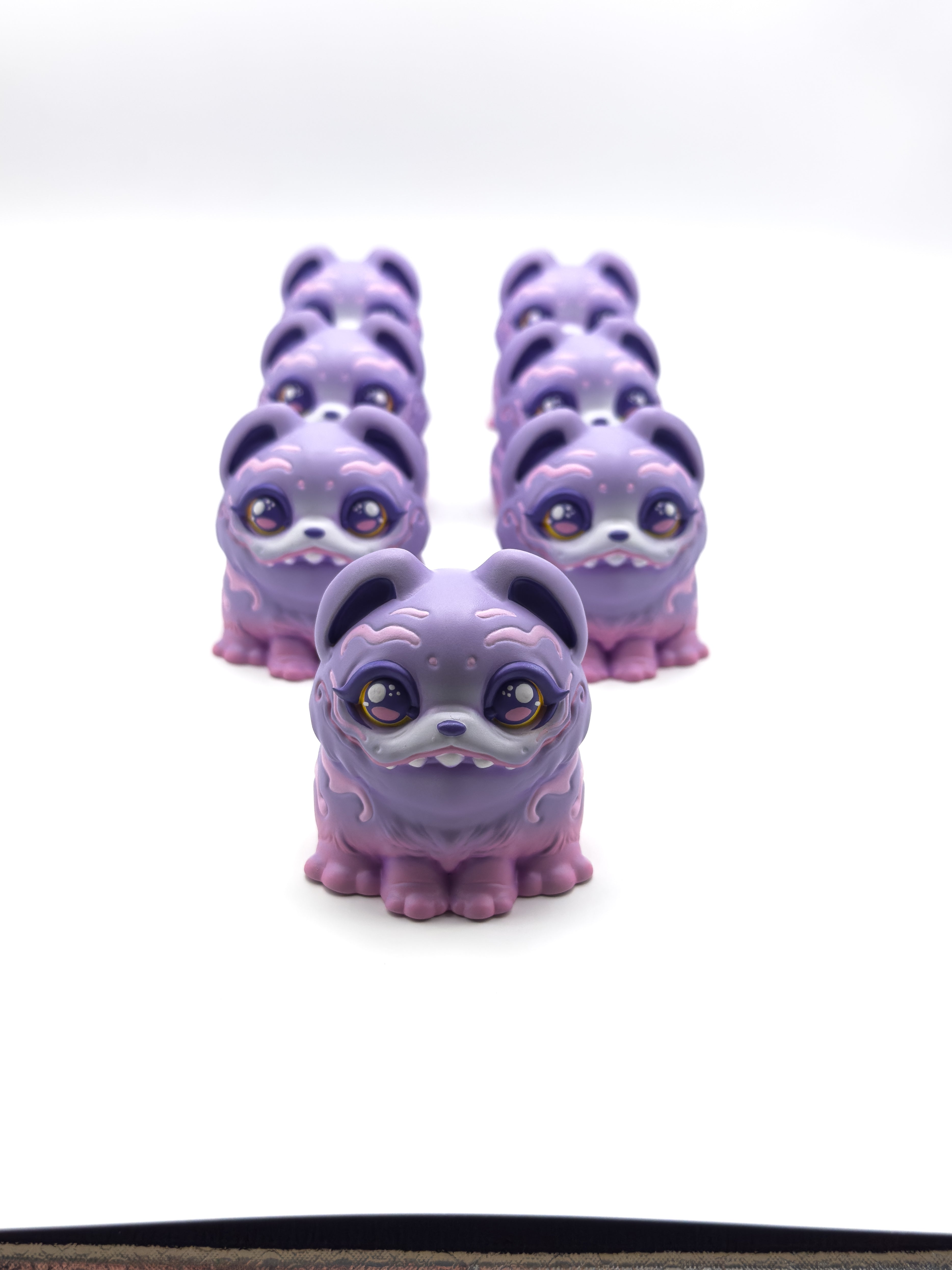 RuRu by Tomodachi Island: six 4 resin dog-like figurines with big glittery eyes, fangs, and swirling markings, arranged in a pyramid, limited to 10 pieces.